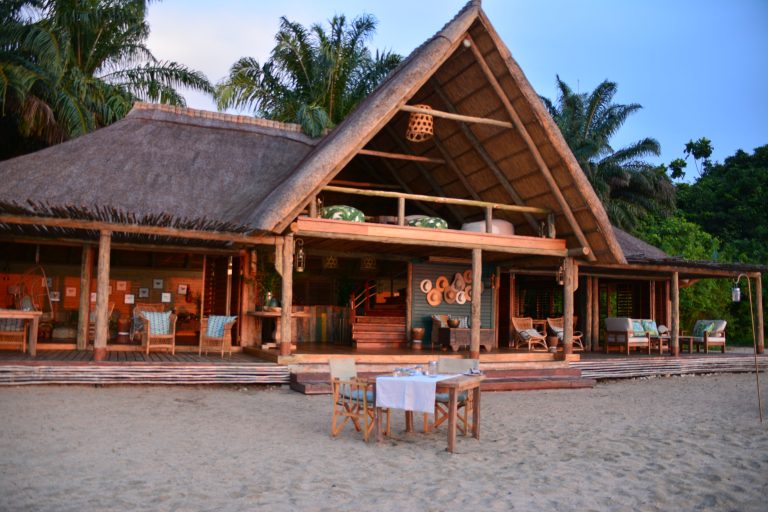 Beach dinner table set before thatched lounge, Mahale Mountains National Park, Tanzania