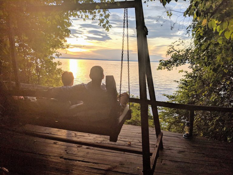 Couple on swing seat watching golden sunset, Mahale Mountains National Park, Tanzania