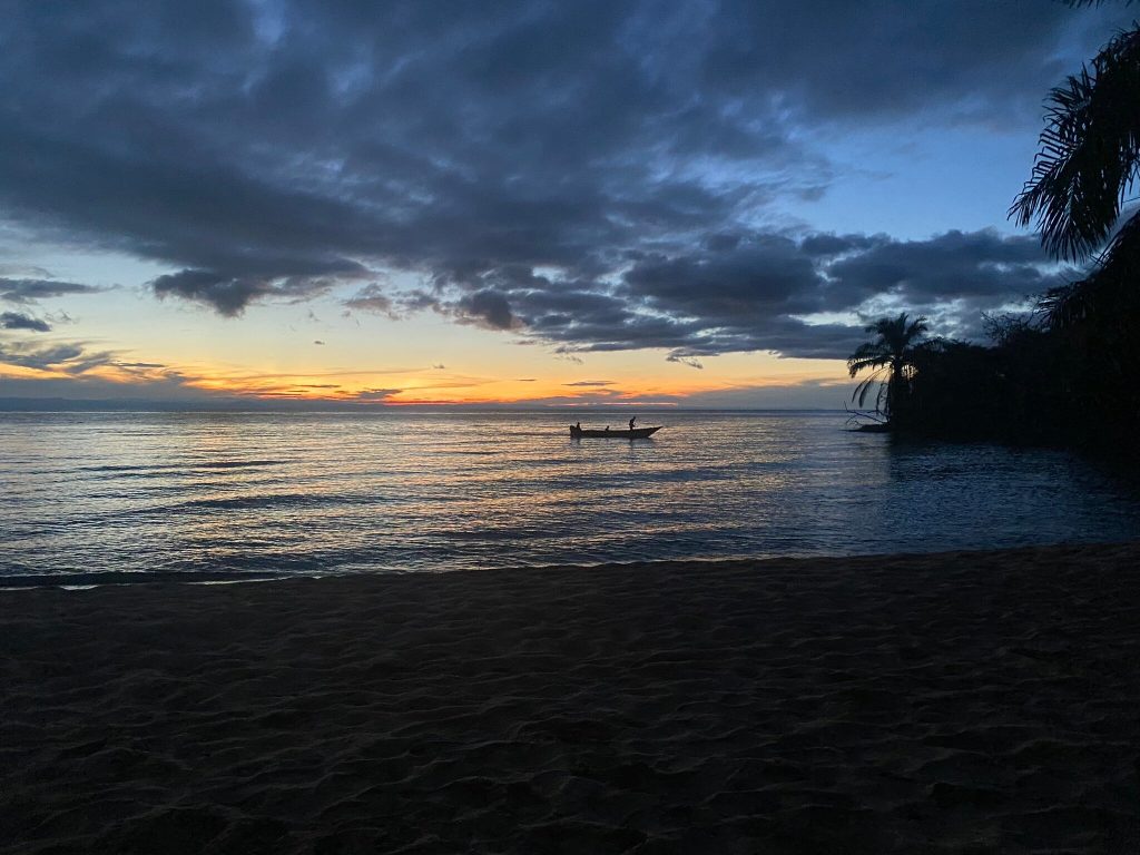 Fishermen boat silhouetted against orange dusk horizon, Mahale Mountains National Park, Tanzania