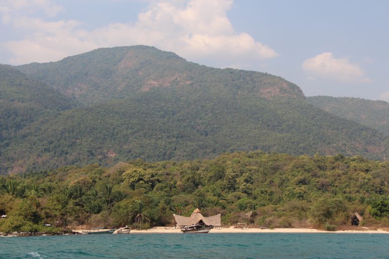 Forested mountain rising above tiny beach camp from the lake, Mahale Mountains National Park, Tanzania