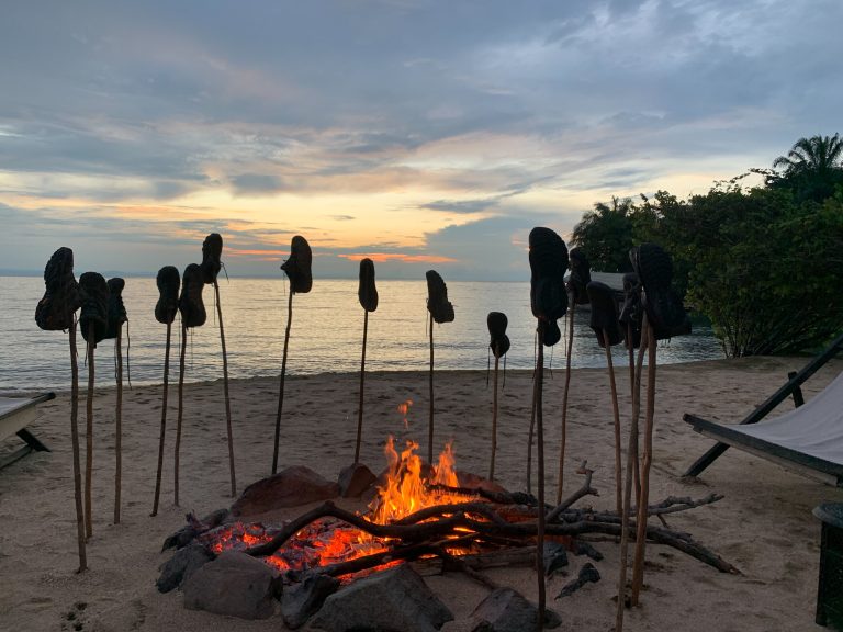 Hiking boots drying on sticks around beach campfire at dusk, Mahale Mountains National Park, Tanzania
