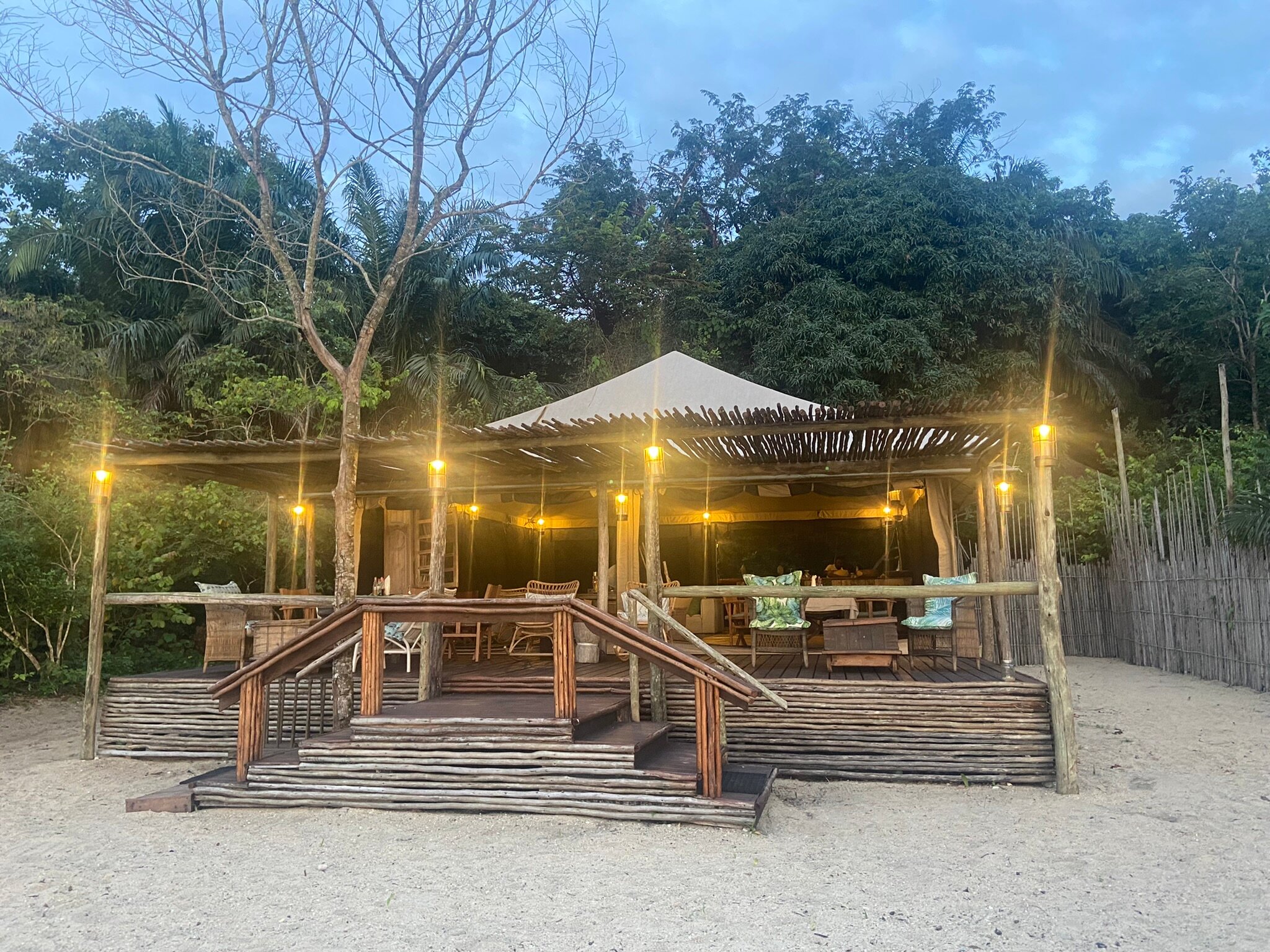 Lantern-lit open-fronted lounge banda on the sand at dusk