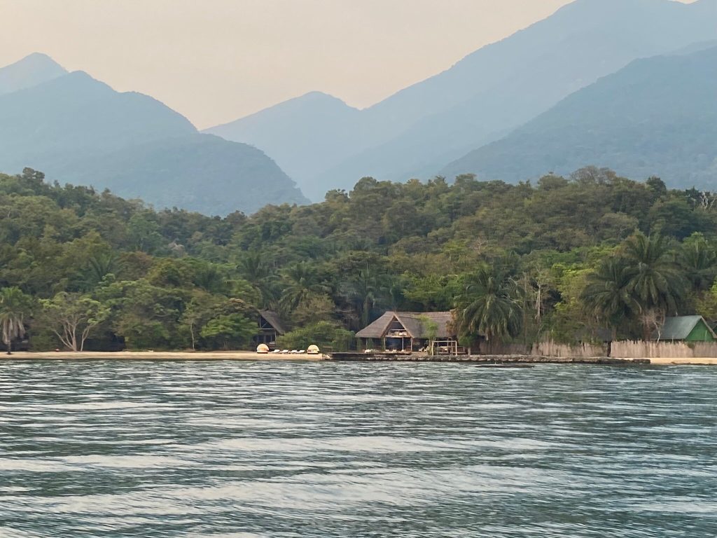 Lodge bandas below hazy blue mountain ridges, Mahale Mountains National Park, Tanzania