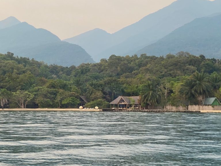 Lodge bandas below hazy blue mountain ridges, Mahale Mountains National Park, Tanzania