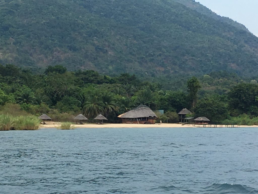 Round thatch dining hut and beach umbrellas from the water, Mahale Mountains National Park, Tanzania