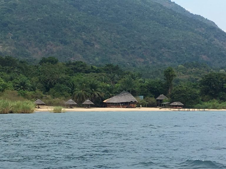Round thatch dining hut and beach umbrellas from the water, Mahale Mountains National Park, Tanzania