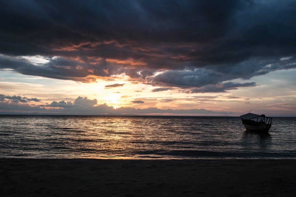 Single canopied boat silhouetted at stormy sunset, Mahale Mountains National Park, Tanzania