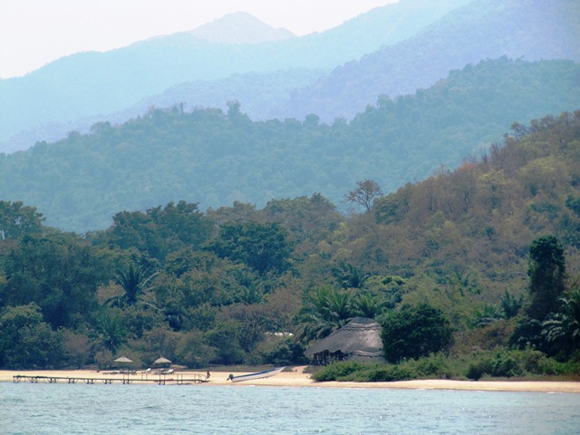 Thatched banda and jetty seen from the lake, Mahale Mountains National Park, Tanzania
