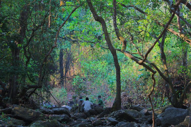 Three guides resting on rocky streambed, Mahale Mountains National Park, Tanzania