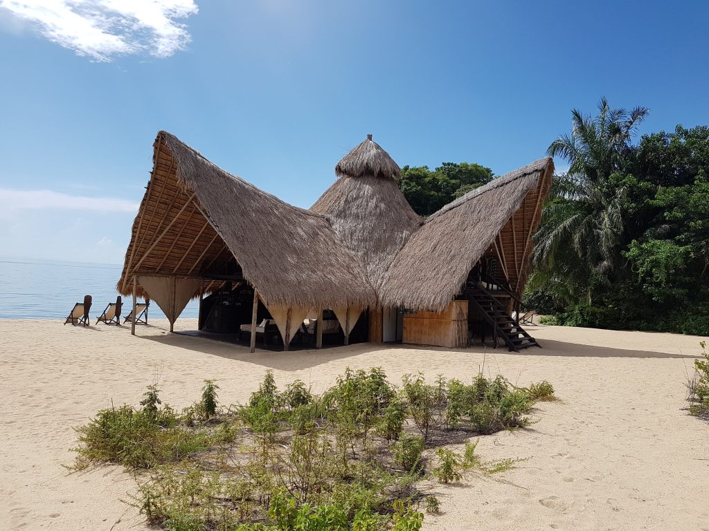 Winged thatched main lodge on white sand under blue sky, Mahale Mountains National Park, Tanzania
